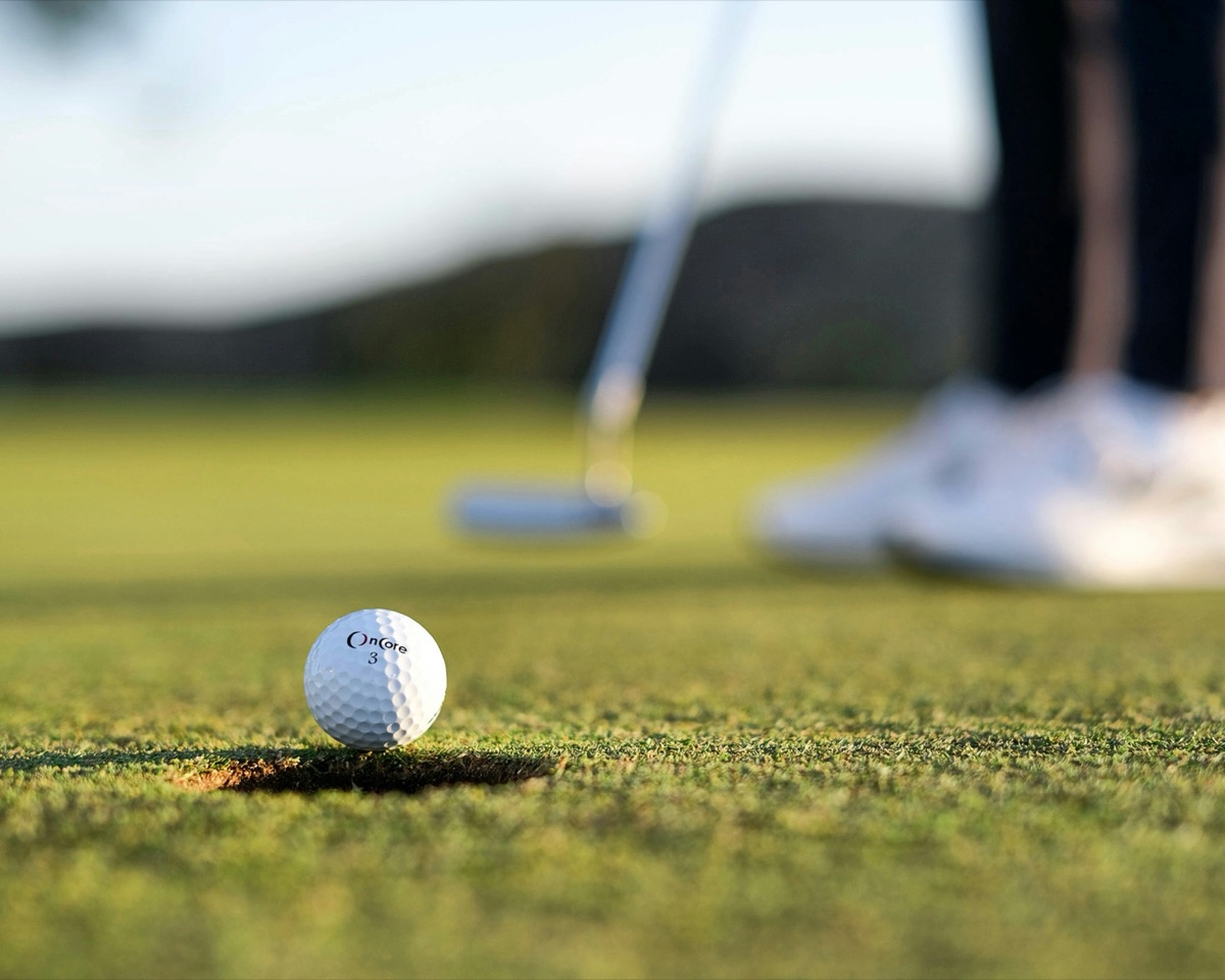Golf ball on the lip of the cup on a putting green